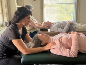 Two people laying on beds getting massaged by two other people