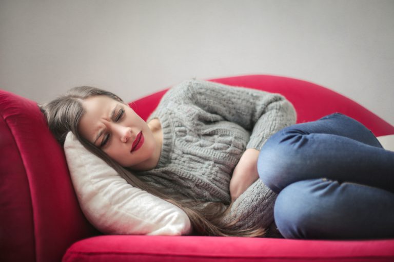 Image of a woman lying on the couch with stomach pain related to GERD.